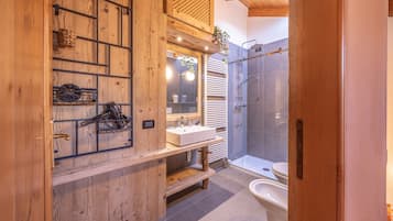 A bathroom with a wooden vanity, a sink, a mirror, and a shower area.