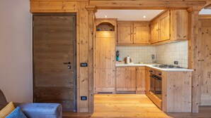 Una cucina in legno con isola centrale, pensili e zoccolo rivestito in piastrelle.
