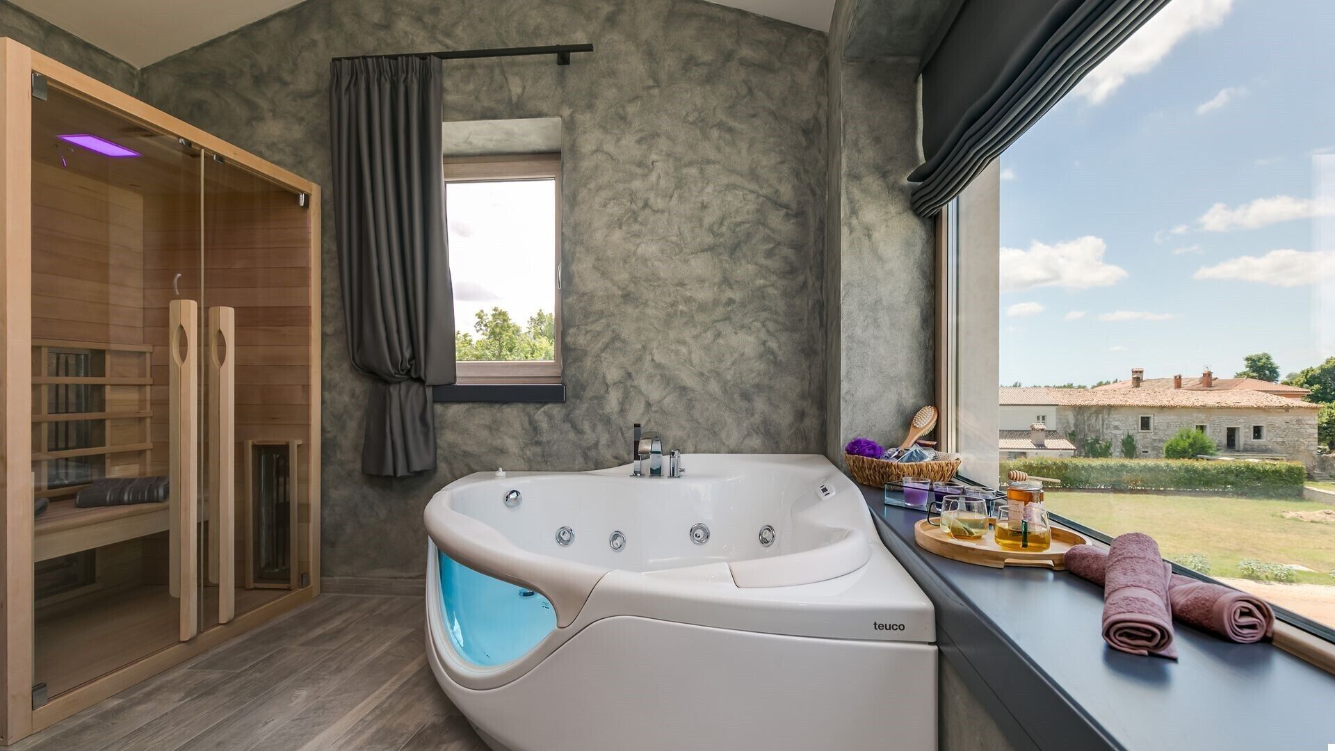A modern bathroom with a freestanding bathtub, a glass-enclosed shower, and a view of the countryside.