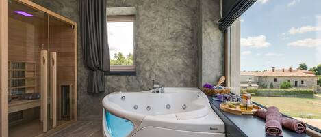 A modern bathroom with a freestanding bathtub, a glass-enclosed shower, and a view of the countryside.