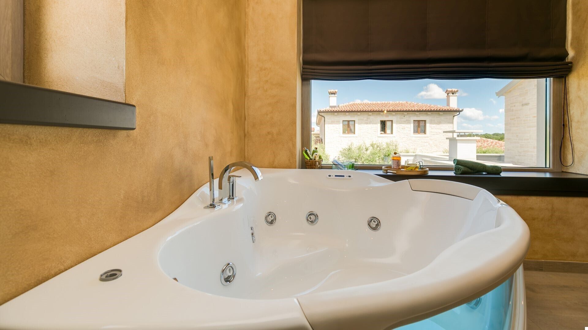 A modern bathroom with a freestanding bathtub, a window with a view of a building, and a towel rack.