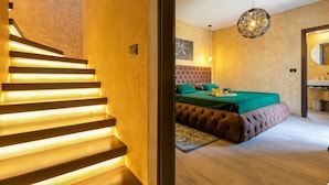 A modern bedroom with a tufted headboard, a green bedspread, and a wooden staircase with illuminated steps. - Lovely Villa Maslina with a pool (Nova Vas)