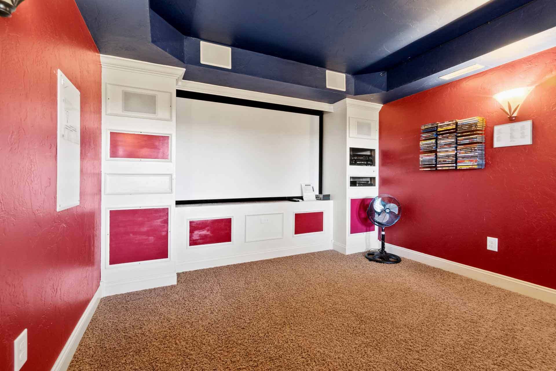 A room with a red and white color scheme, a ceiling fan, and a wall-mounted shelf with CDs.