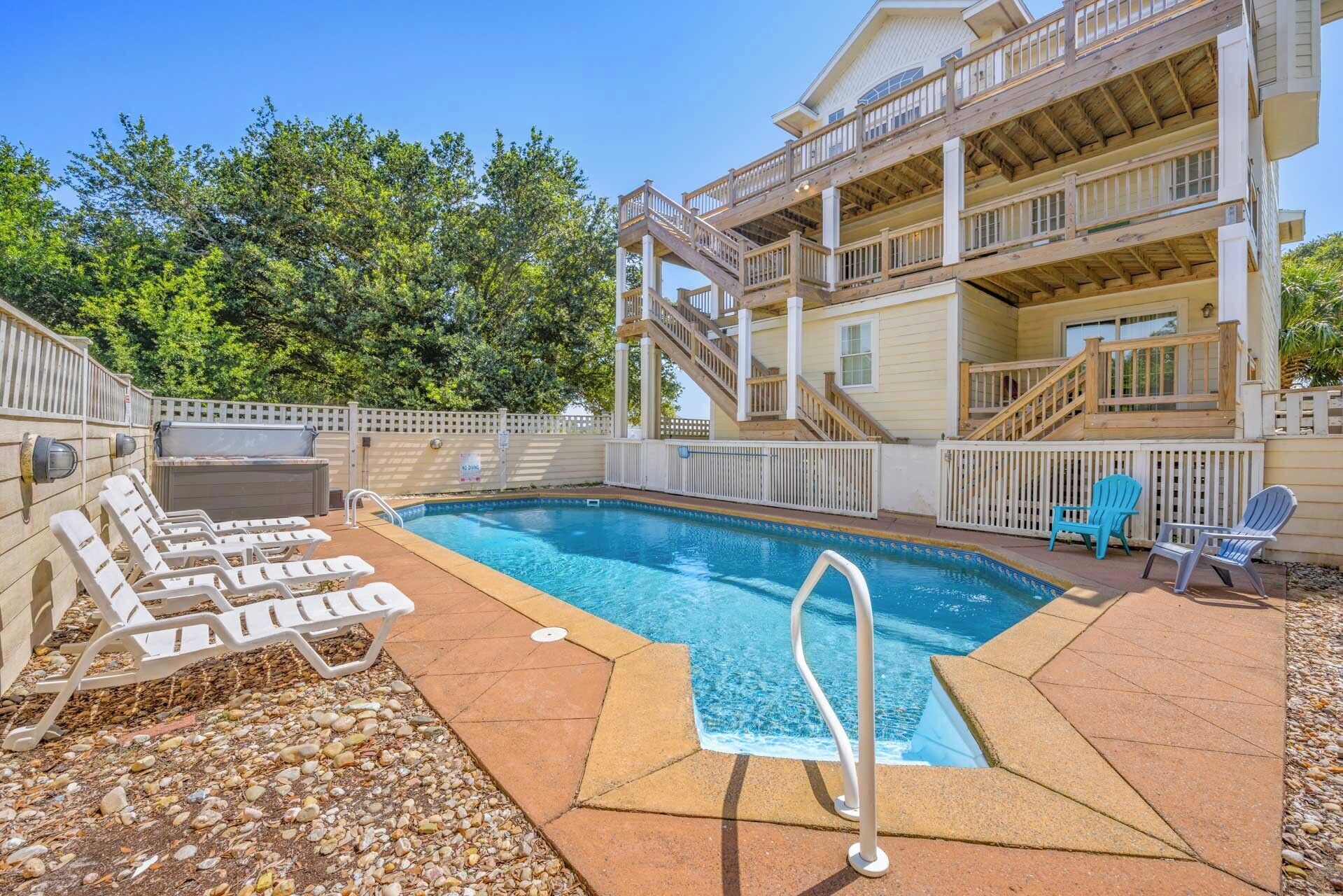 Ein Pool mit Liegestühlen, einer Sonnenterrasse und einem mehrstöckigen Gebäude mit Holzfassade.