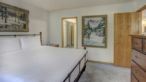 A bedroom with a large bed, a wooden dresser, and two framed paintings on the wall. - Newly Remodeled Spacious 1 Bedroom 1 Condo by RedAwning (Avon)