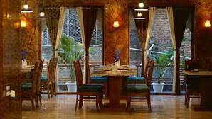 A restaurant with a marble wall, wooden chairs, and a table set for dining. - Spring Sky Udaipur by ShriGo Hotels (Udaipur)