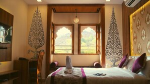 A room with a bed, a chair, a table, and a window with a view of the outdoors. - Spring Sky Udaipur by ShriGo Hotels (Udaipur)