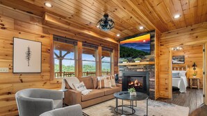 Interior acogedor de una cabaña de madera con chimenea, paredes de madera, un sofá y vistas al exterior.