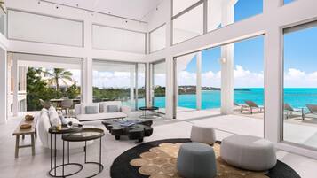 A spacious living area with a large window overlooking a turquoise sea and a clear sky.