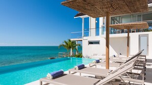 Un espace aménagé au bord de la piscine, avec des chaises longues et une vue sur l’océan.