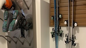 Een ski-rek met ski's en schoenen, een houten wand en een bord met een tekst.