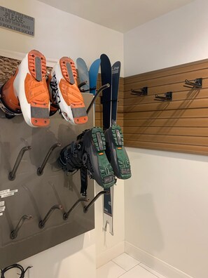 Un porte-skis fixé au mur, sur lequel sont rangées différentes paires de chaussures de ski et de fixations.