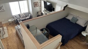 Een compact studio-appartement met een hoogslaper, een klein zitgedeelte en een kitchenette.