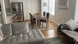 Een moderne keuken met witte kasten, een roestvrijstalen koelkast, en een eethoek met een houten tafel en stoelen.