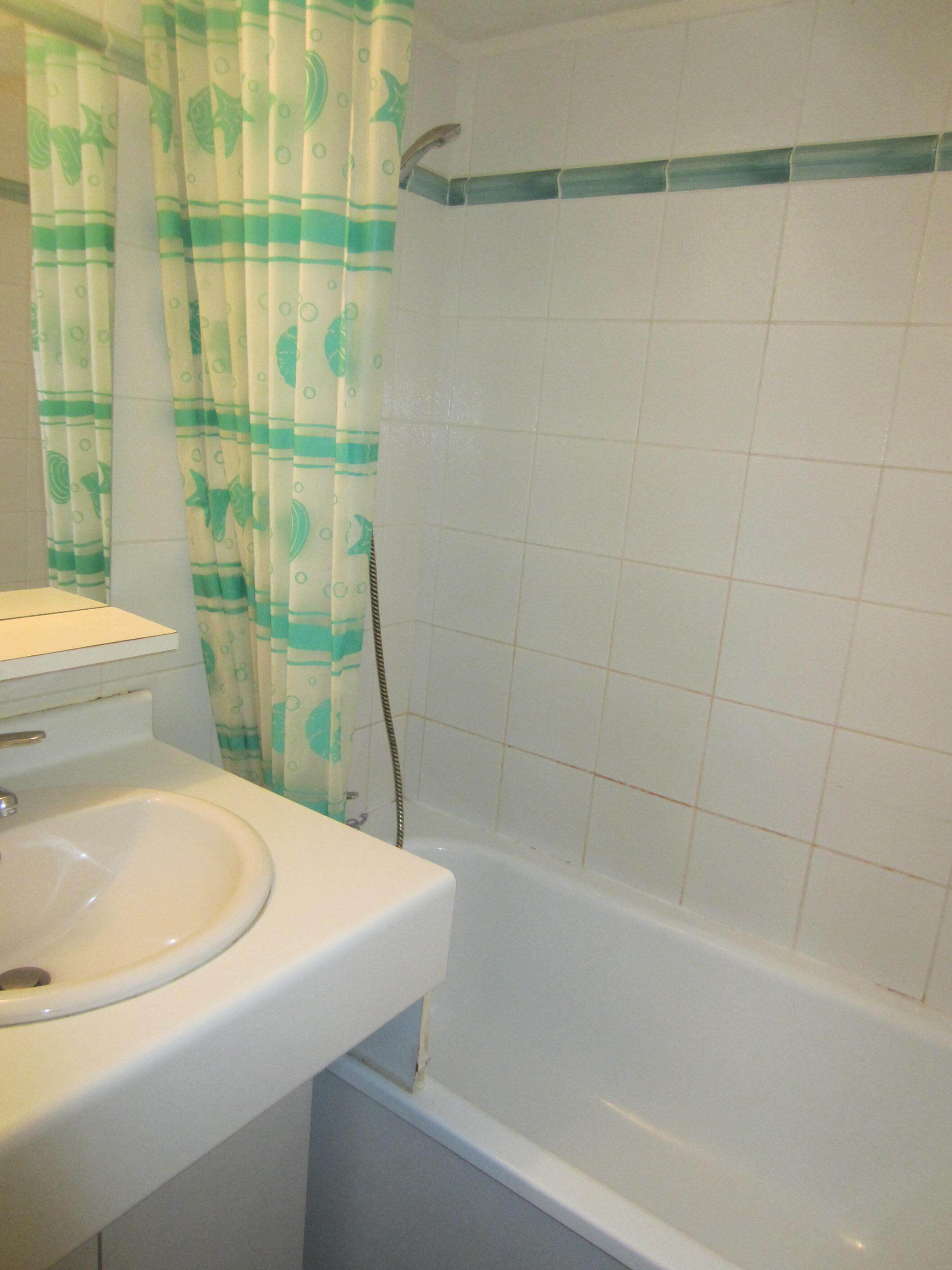 A bathroom with a bathtub, a sink, and a shower curtain with a fish pattern.