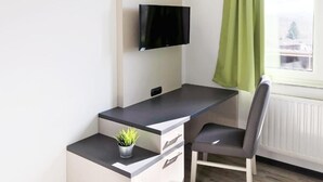A modern room with a desk, chair, and a TV mounted on the wall. - bp24 Hotel Eschweiler (Eschweiler)