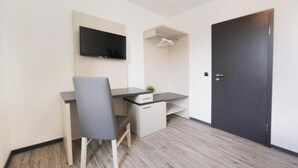 A small, modern room with a desk, chair, and a TV mounted on the wall. - bp24 Hotel Eschweiler (Eschweiler)