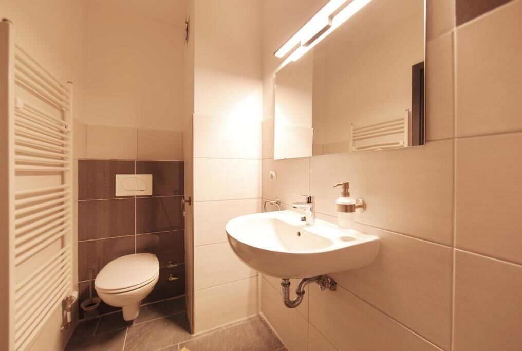 Une salle de bain moderne avec un lavabo blanc, des toilettes et un miroir.