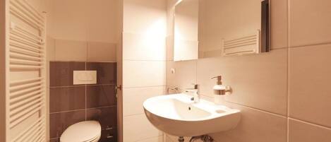 Un baño moderno con un lavamanos blanco, un inodoro y un espejo.