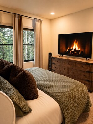 Een slaapkamer met een bed, een dressoir, een televisie en een open haard.