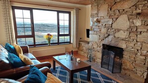 Una sala de estar acogedora con chimenea de piedra, sofá de cuero y un ventanal con vistas al campo.