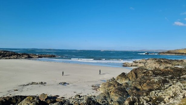 Una playa con terreno rocoso y un cielo azul despejado.