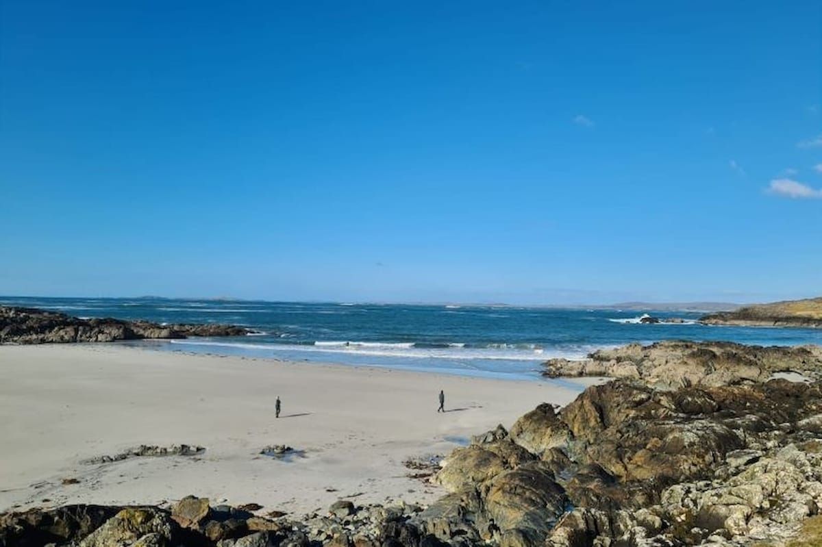 A beach with rocky terrain and a clear sky.