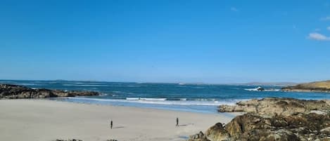 A beach with rocky terrain and a clear sky.