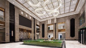 Un vestíbulo amplio con una fuente central, techos altos con luminarias circulares y un diseño arquitectónico moderno.