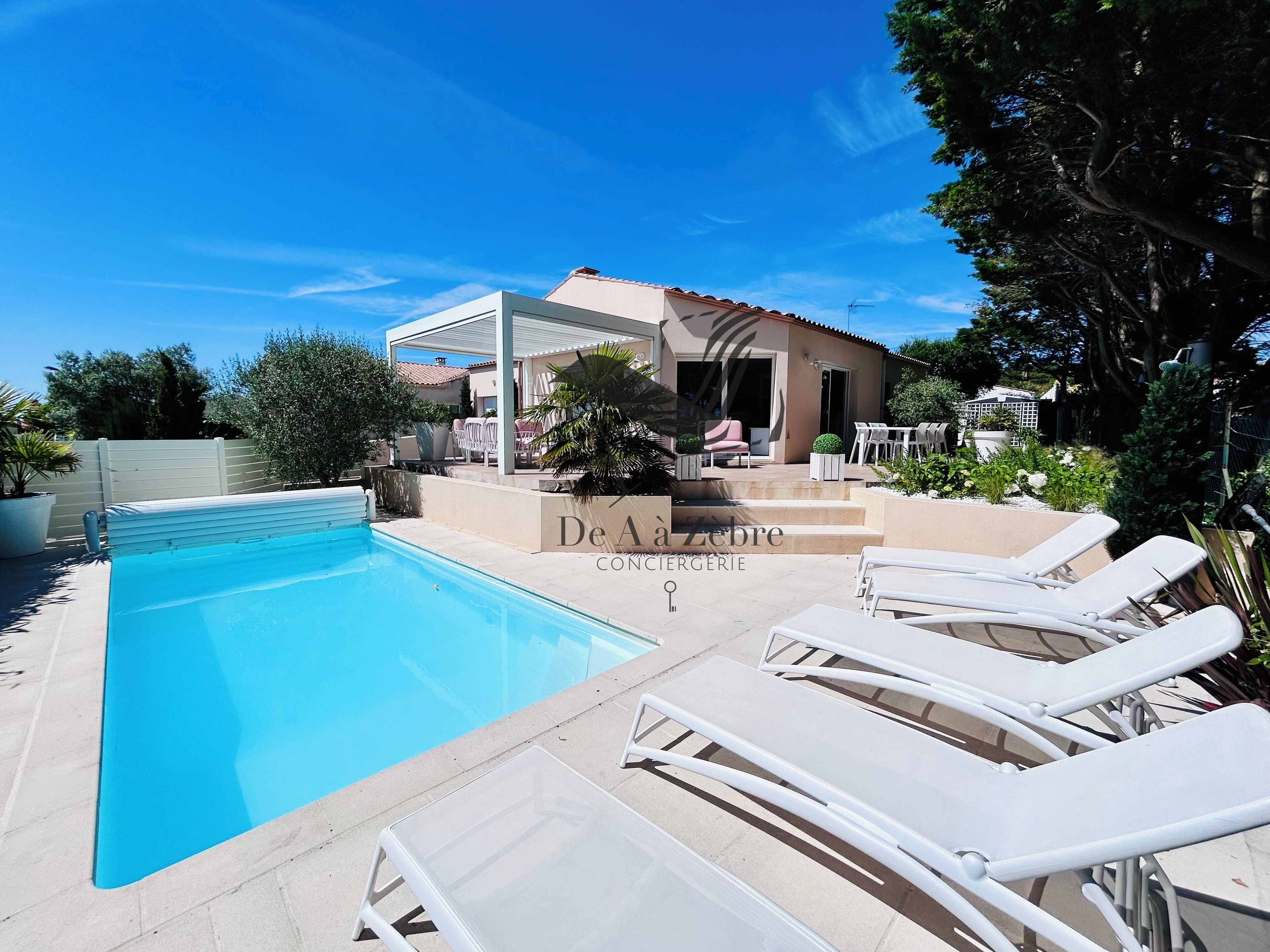 A pool area with lounge chairs and a covered seating area.