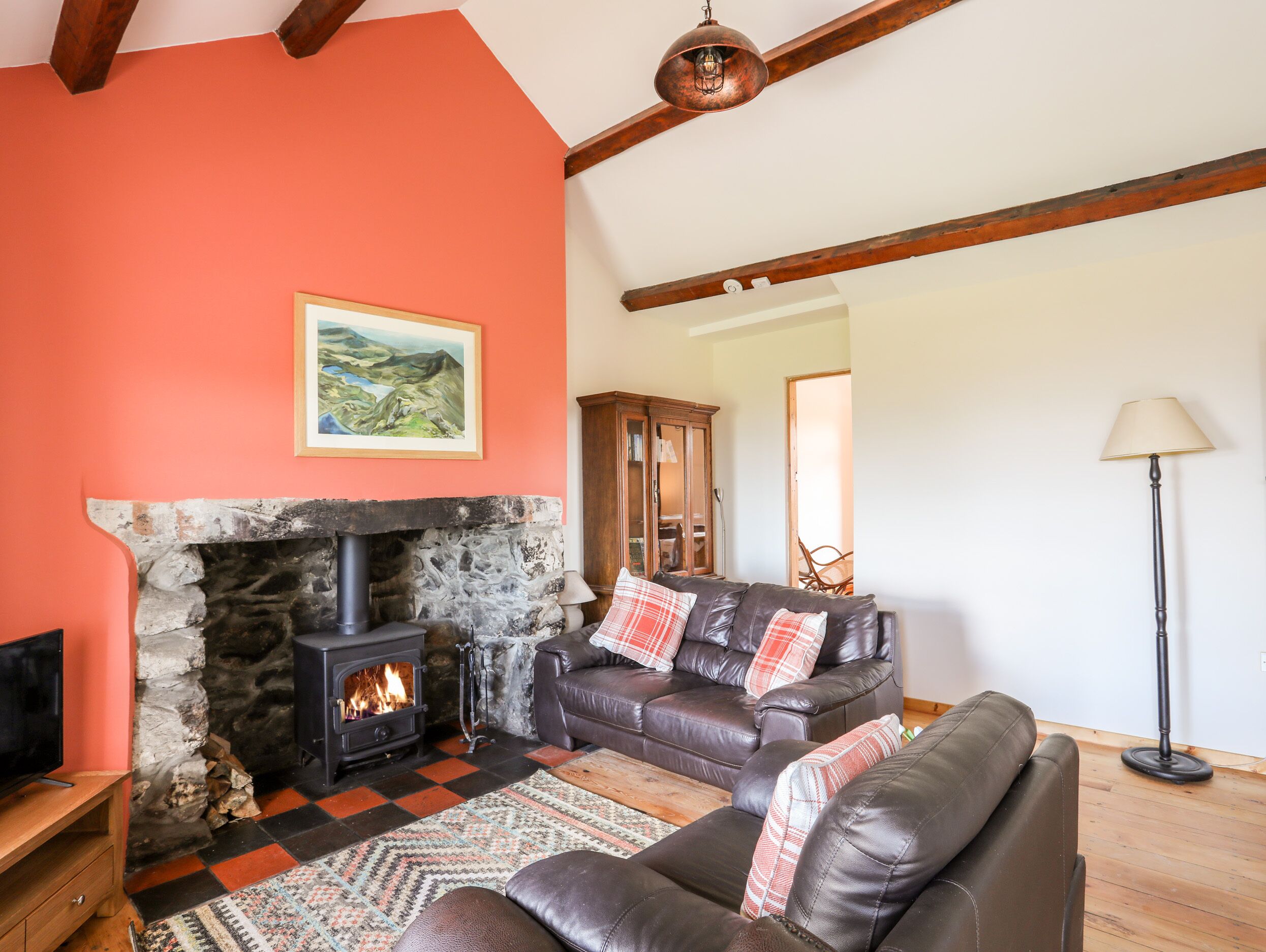 Una sala de estar acogedora con chimenea de piedra, sofá de cuero y un cuadro en la pared.