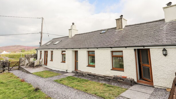 A white house with a grey tiled roof, a stone pathway, and a grassy yard. - Penrallt Fawr (Caernarfon)