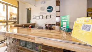 A hotel reception area with a marble counter, framed certificates on the wall, and a QR code sign for digital services. - Ayenda Parque del Quindio (Armenia)