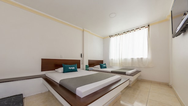 A hotel room with a large bed, a smaller bed, a desk, and a TV. - Ayenda Parque del Quindio (Armenia)