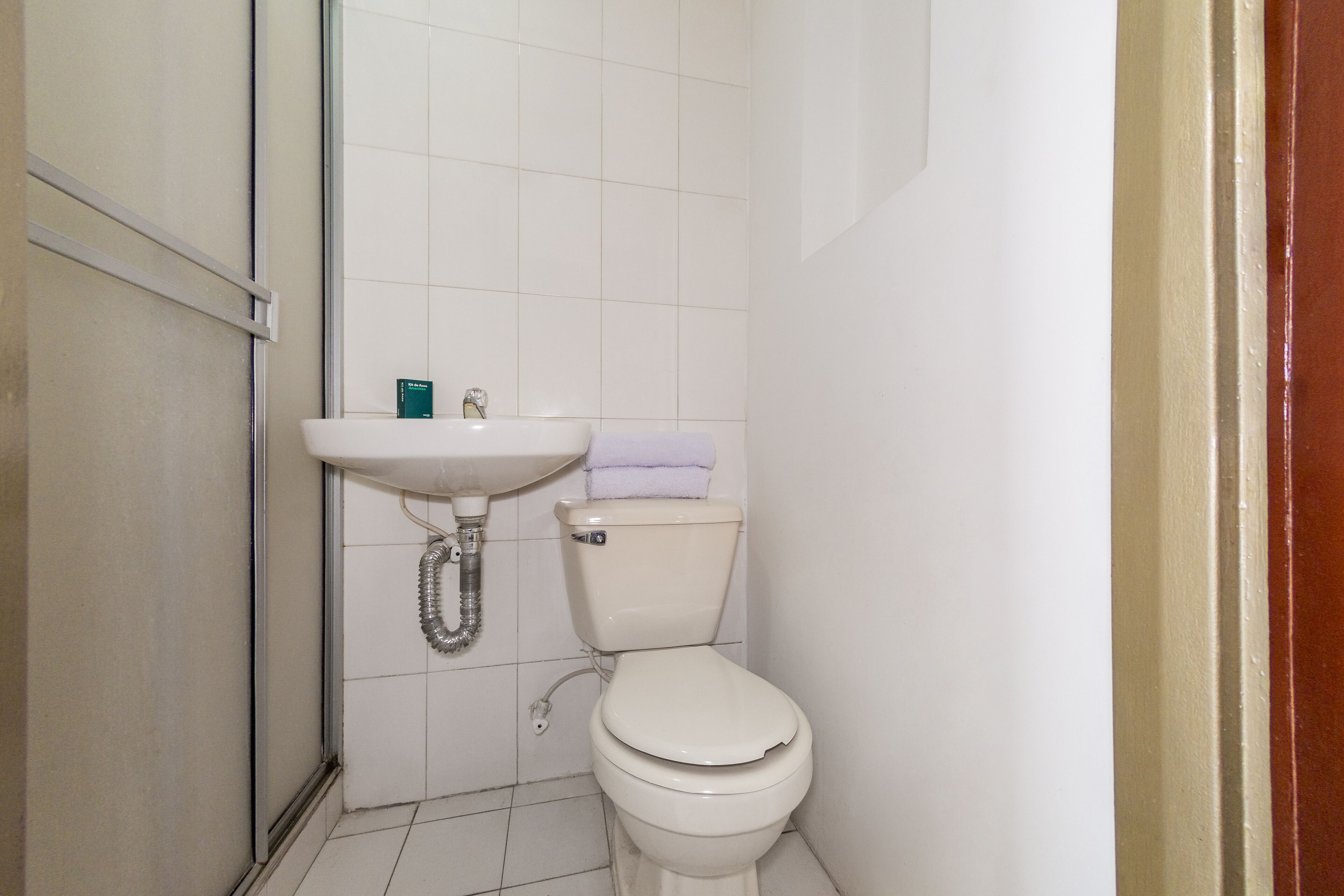 A small bathroom with a white toilet, a sink, and a shower area.