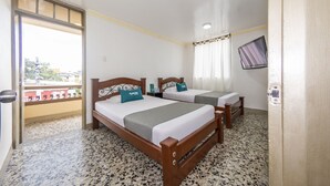 A hotel room with two wooden beds, a small table, a TV, and a balcony with a city view. - Ayenda Parque del Quindio (Armenia)