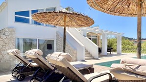 Une maison moderne dotée d’une piscine, de chaises longues et d’un escalier.