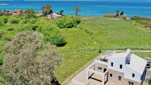 Une propriété située sur la côte, dotée d’une grande pelouse, d’un bâtiment en pierre avec un toit plat et offrant une vue sur la mer.