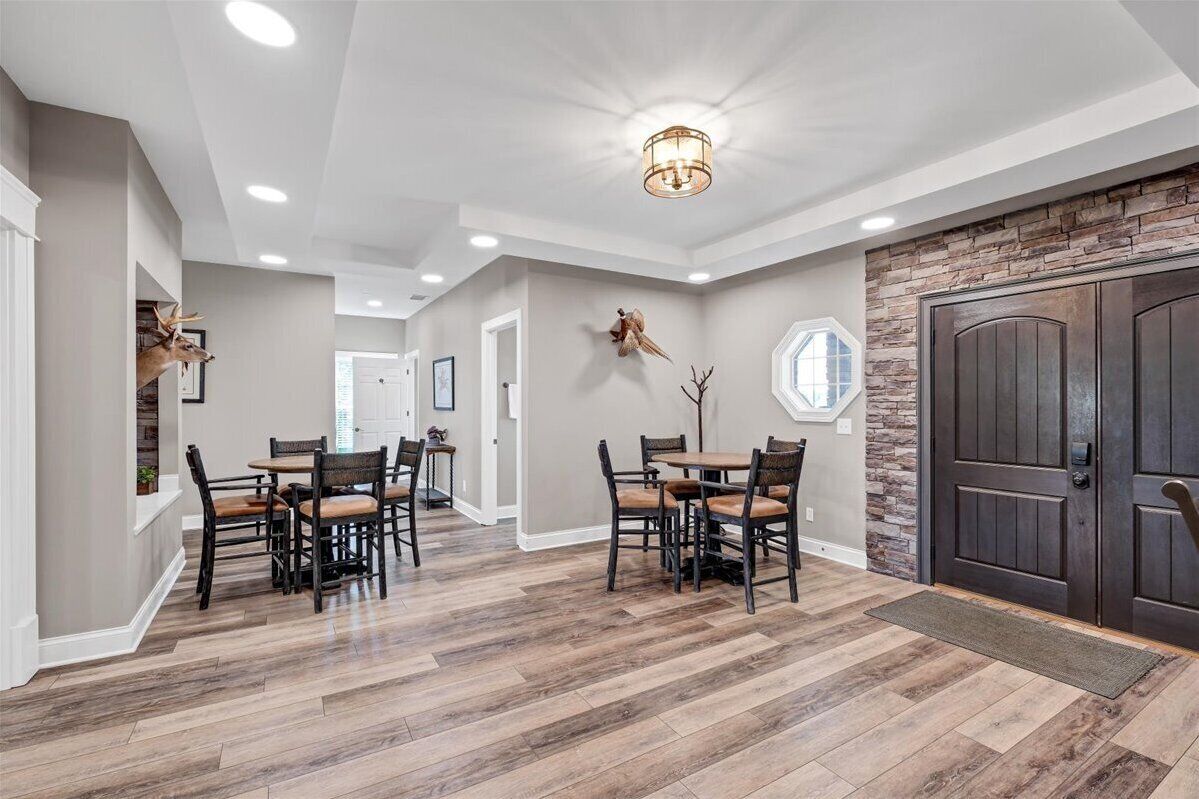 A spacious dining area with a large table and chairs, a stone accent wall, and a dark wooden door.
