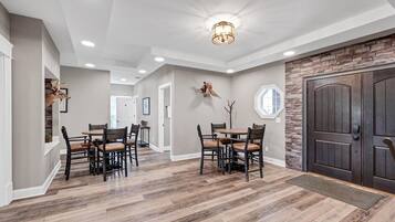 A spacious dining area with a large table and chairs, a stone accent wall, and a dark wooden door.