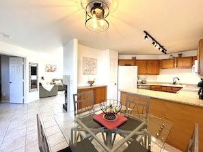 A modern kitchen with wooden cabinets, a glass dining table, and a central island.
