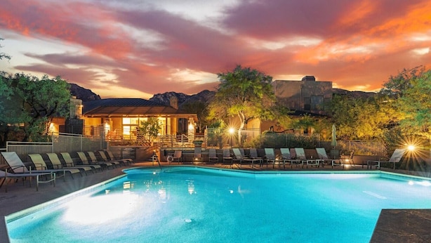 A swimming pool with lounge chairs and a building in the background.