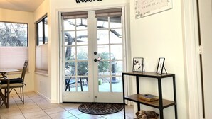 A clean, welcoming entryway with a 'welcome' sign above a glass door, a bench, and a shelf with decorative items.