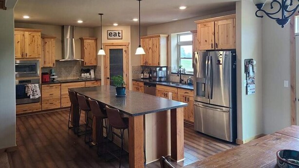 Una cocina moderna con armarios de madera, electrodomésticos de acero inoxidable y una isla central con taburetes de bar.