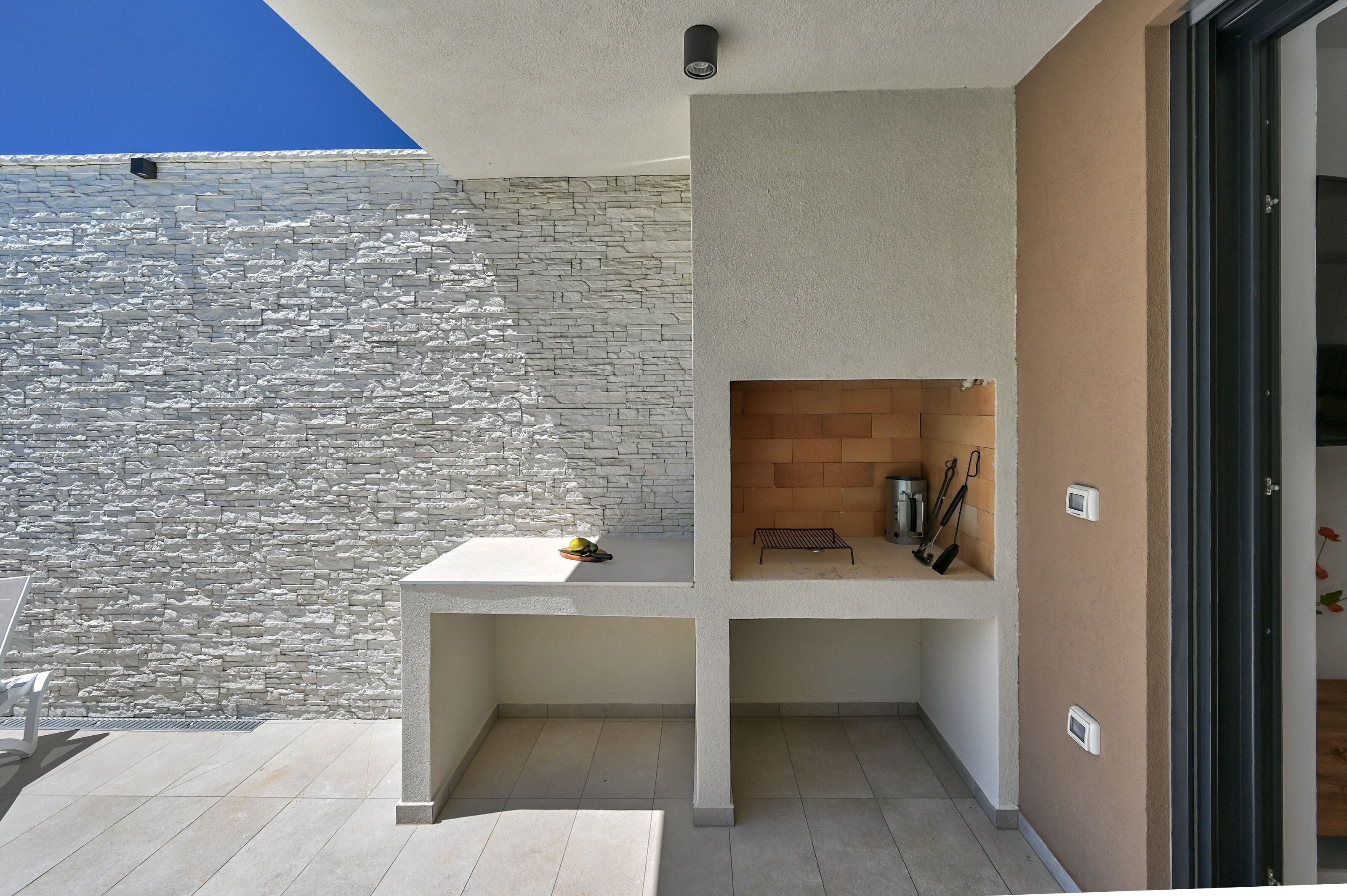 Ein moderner Balkon mit Steinwand, einem kleinen Tisch und einer eingebauten Ablage für Küchenutensilien.