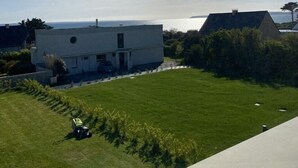 A modern house with a large lawn and a view of the sea.