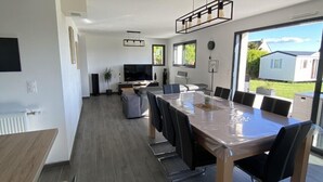 A modern kitchen with a large dining table, built-in appliances, and a view of the outdoors.
