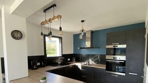 A modern kitchen with a central island, black cabinets, and stainless steel appliances.