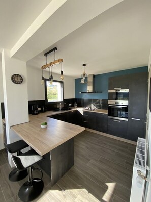 Una cocina moderna con una isla central, armarios negros y electrodomésticos de acero inoxidable.