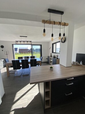 Una cocina moderna con una isla grande, gabinetes negros e iluminación colgante.